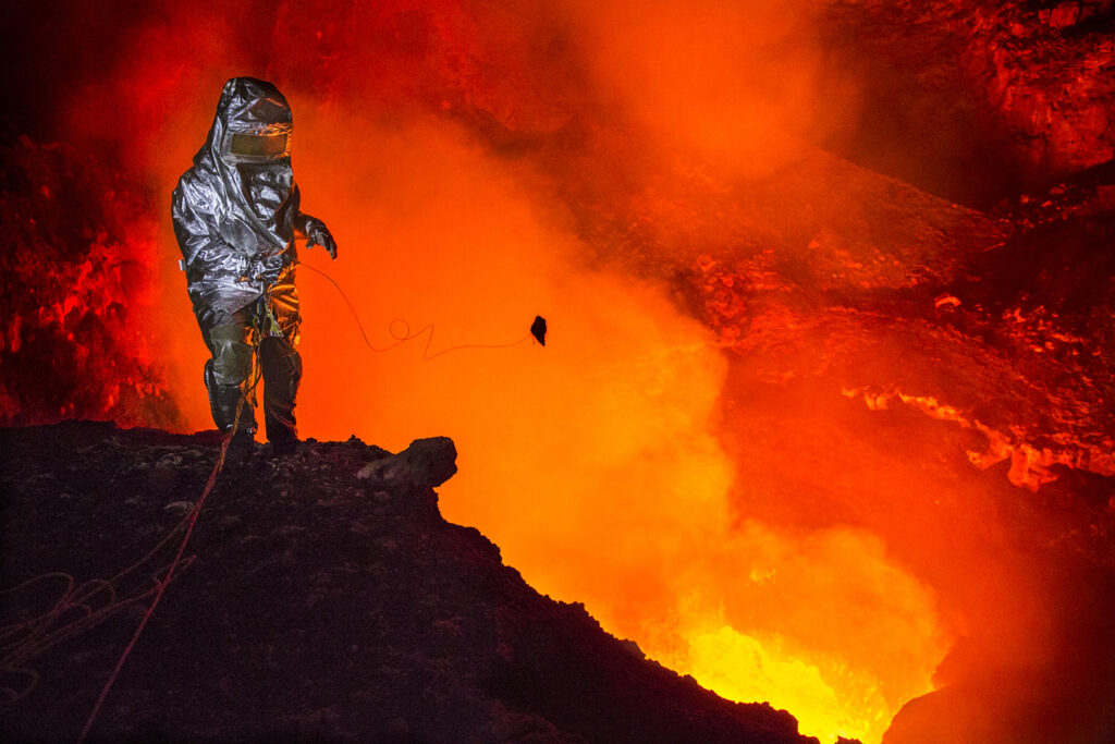 Sebastian Hofmann wagt sich mit Hitzeschutzanzug geschützt an den Kraterrand. 50m über dem See ist die Strahlungswärme der 1200 Grad heißen Lava so hoch, dass man ohne Hitzeschutzanzug verbrennen würde. Er wirft eine Lavabombe mit einem Spezialseil, um an eine Probe der frischen Lava zu kommen. Boyer erhofft sich dadurch Hinweise auf die Gaszusammensetzung und damit Explosivität des Sees.