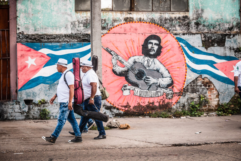 Mittelamerika, Karibik, Kuba, Havanna. Distrikt Playa. Taxi- und Busstation an der Quinta Avenida (Avenida 5ta), Fuenfte Allee. Mit Strassenkunst. Revolutionaer Che Guevara als Musiker.

Central America, Caribbean, Cuba, Havana. District of Playa. Taxi and bus station on Quinta Avenida (Avenida 5ta), fifth avenue. With street art. Revolutionary Che Guevara as a musician.